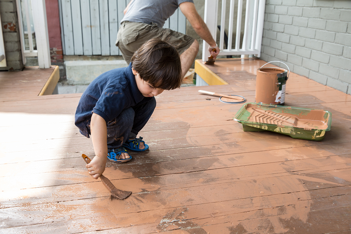 Child and grandfather painting the patio floor